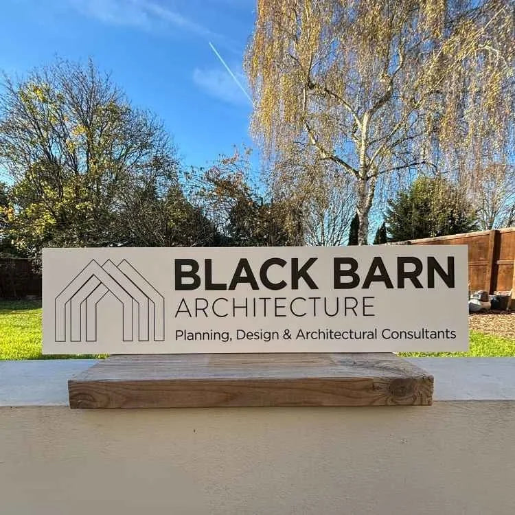 Black Barn Architecture sign with trees and blue sky in the background
