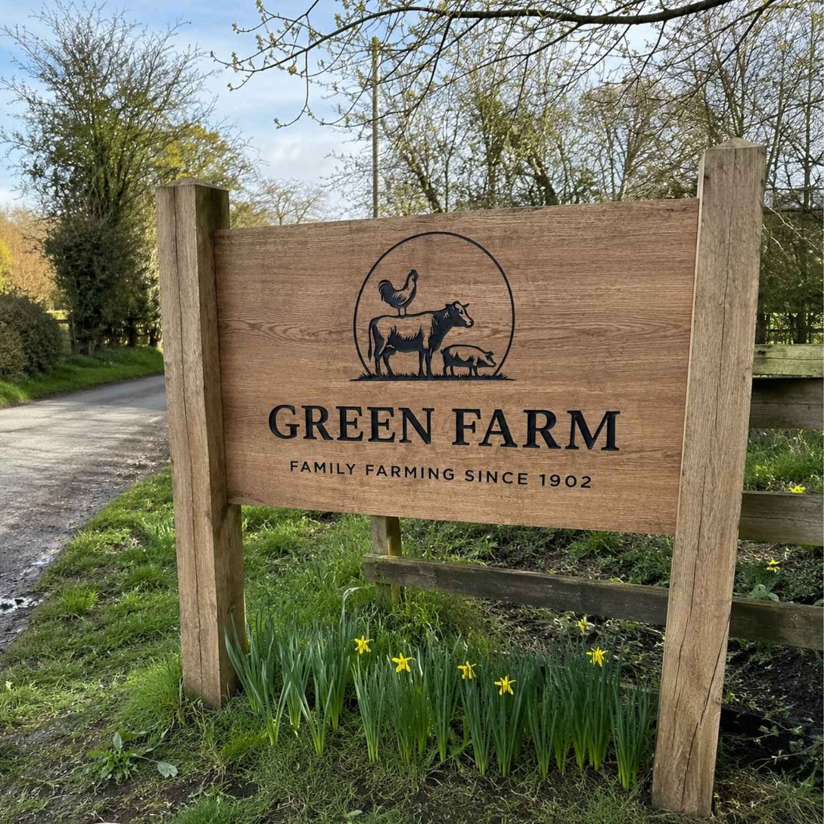 Wooden sign for Green Farm with farm animals illustration and text on a grassy area.