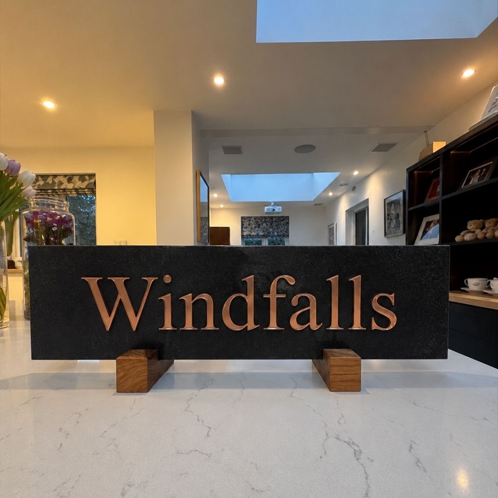 A charcoal horizontal sign with the word 'Windfalls' in large copper-toned letters.