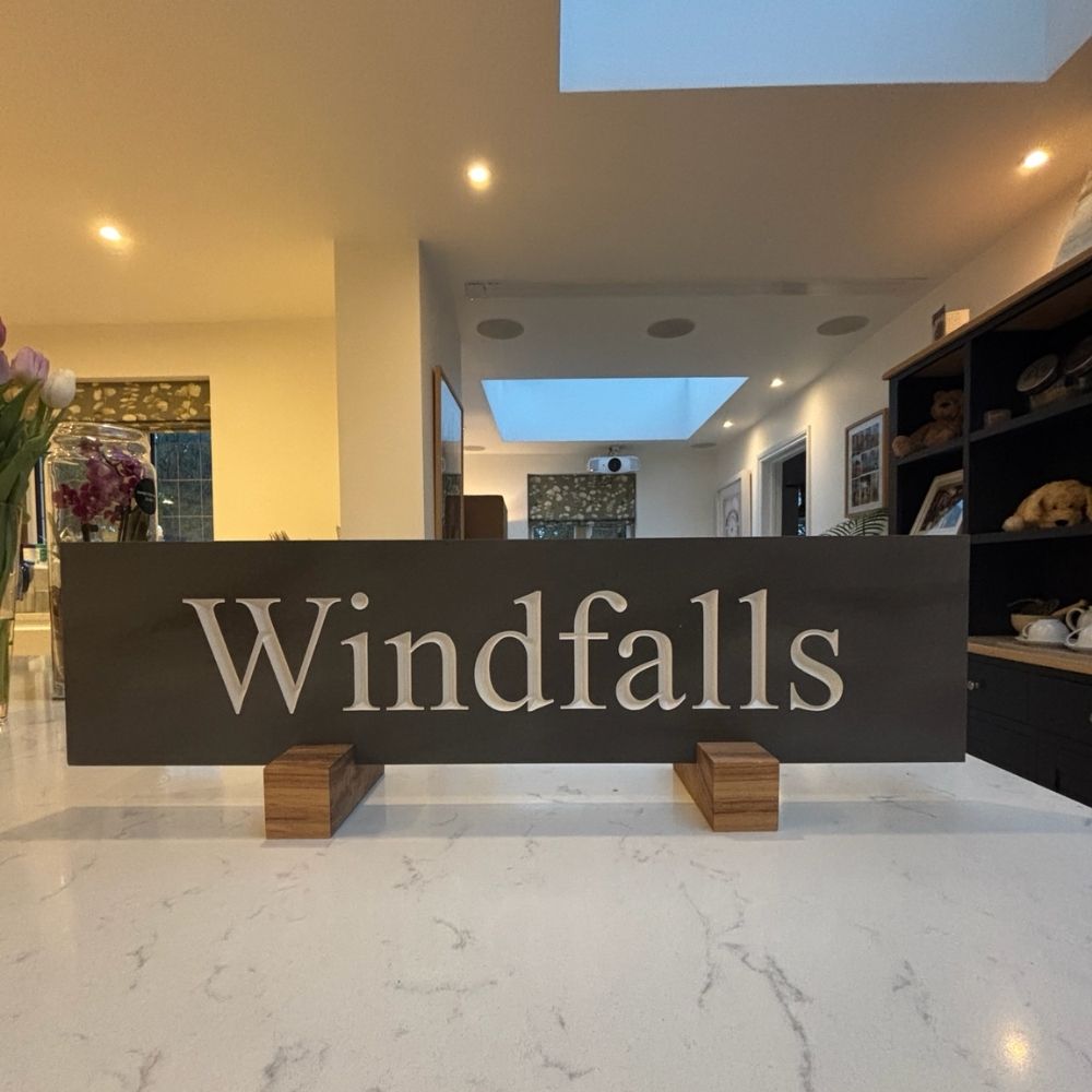 A dark slate sign with the name 'Windfalls' in white serif lettering.