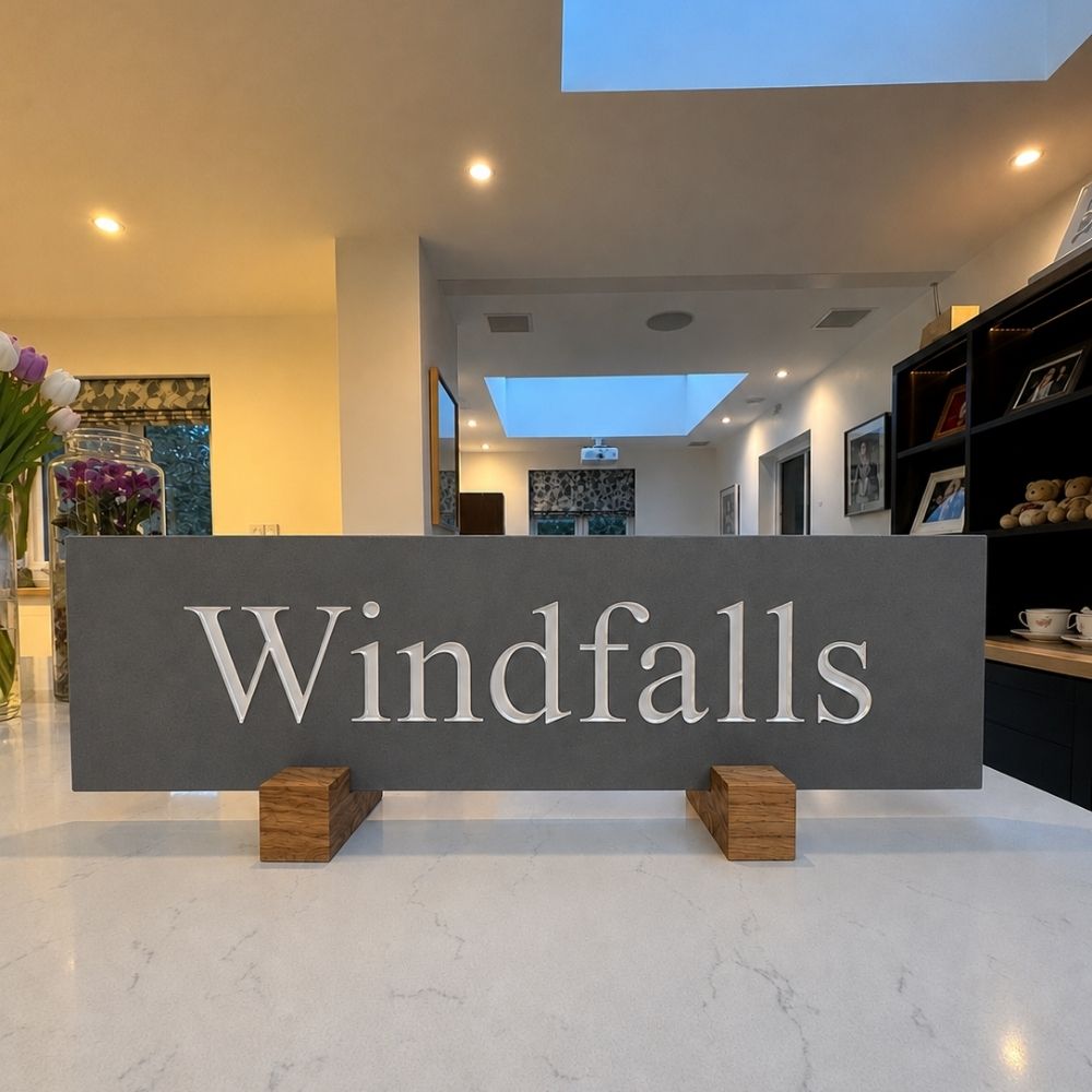 A large horizontal grey sign with the word 'Windfalls' in white serif letters.