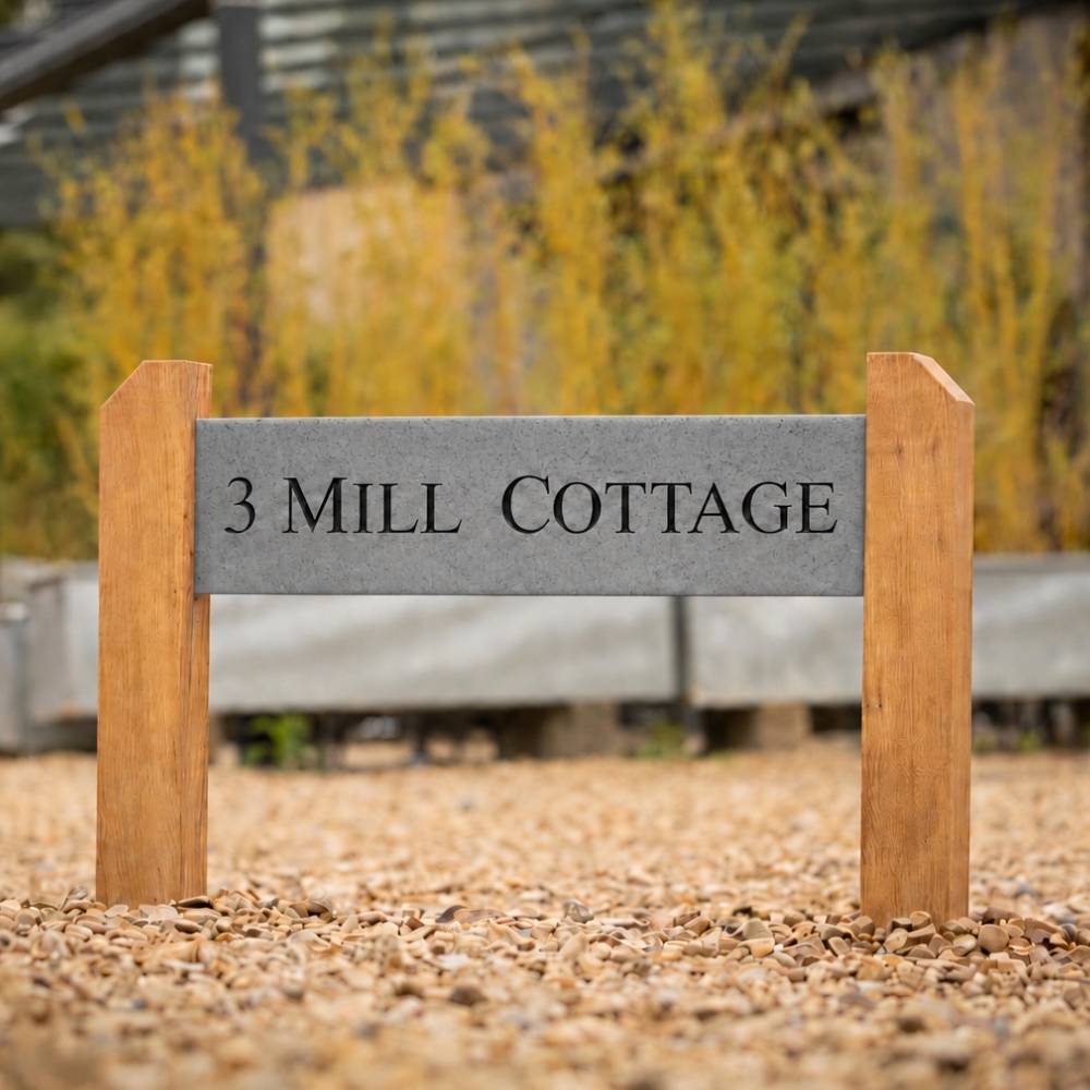 A custom wooden and granite stone address sign for '3 Mill Cottage' standing on a gravel surface outdoors.