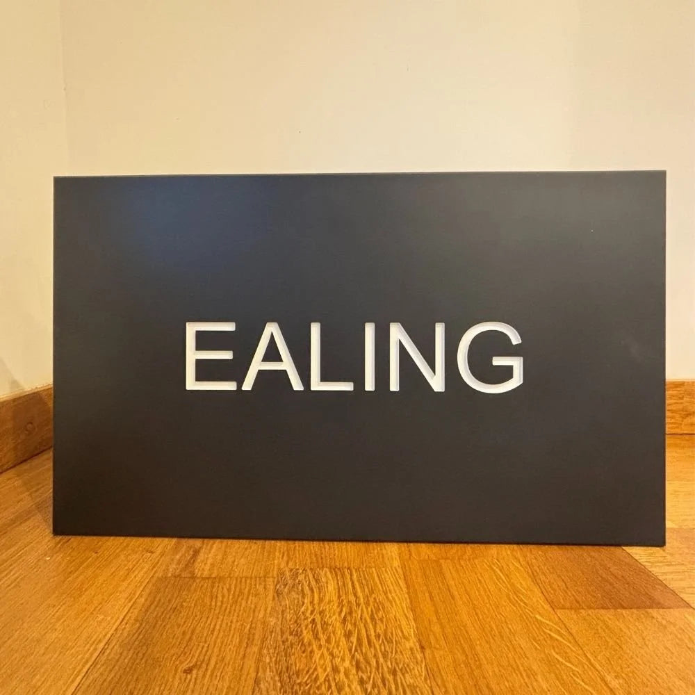 Black board with 'Ealing' written on it on a wooden floor.