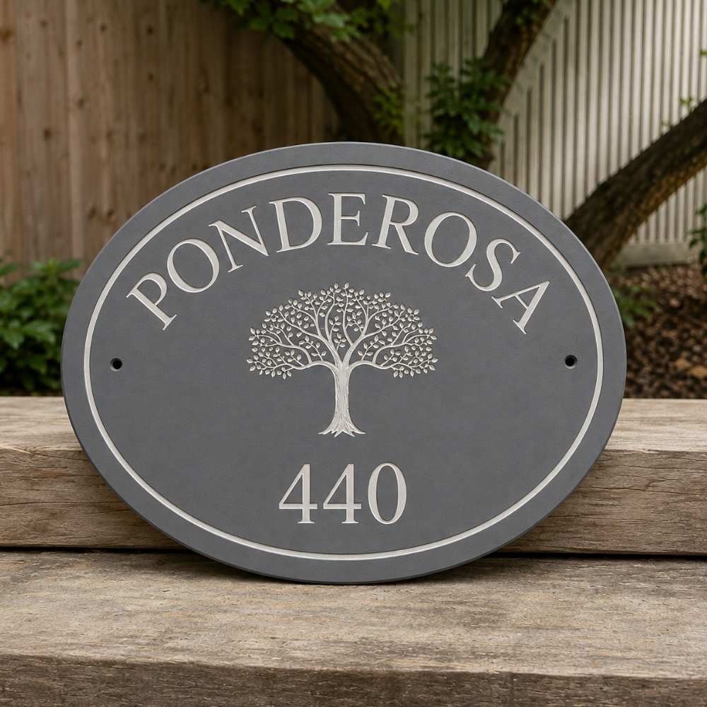 An oval grey house plaque with a silver tree emblem and the text 'PONDEROSA 440', displayed on a wooden surface outdoors.