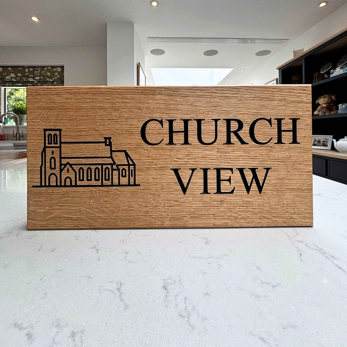 Wooden sign with 'Church View' and a church illustration in a modern indoor setting.