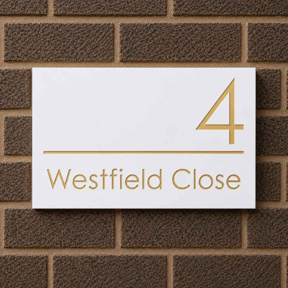 A white rectangular house number sign with gold lettering reading 'Westfield Close' and a large gold number 4, mounted on a brown brick wall.