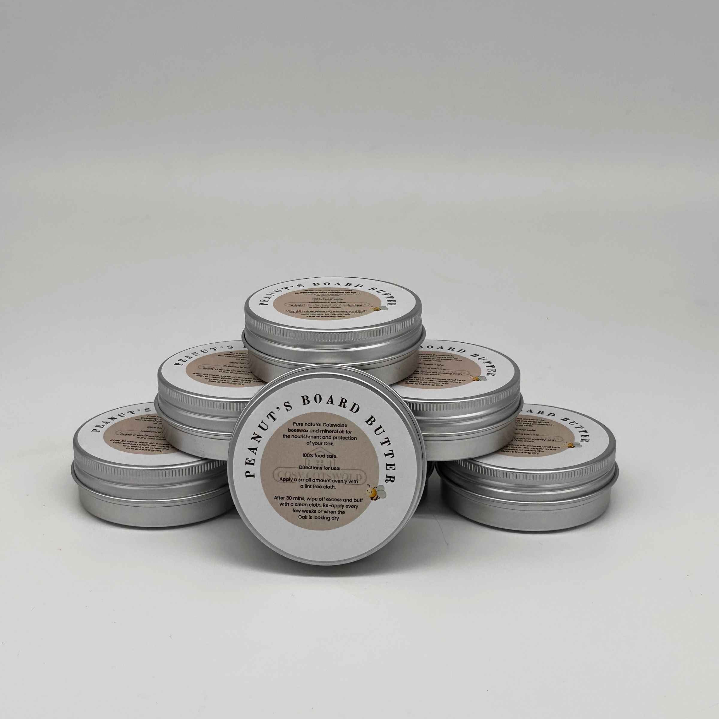 Stack of metal tins labeled 'Peanut's Board Butter' on a white background
