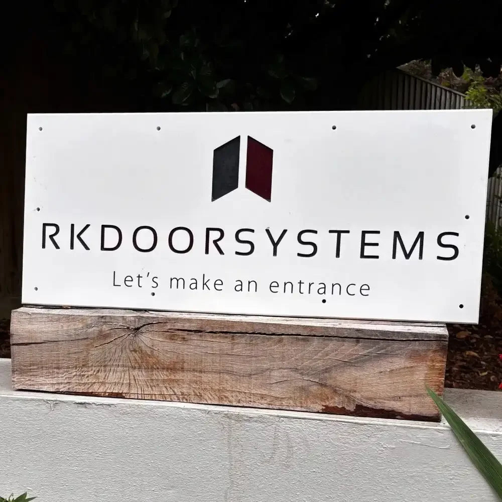 RKDOORSYSTEMS sign on a wooden base with a dark background