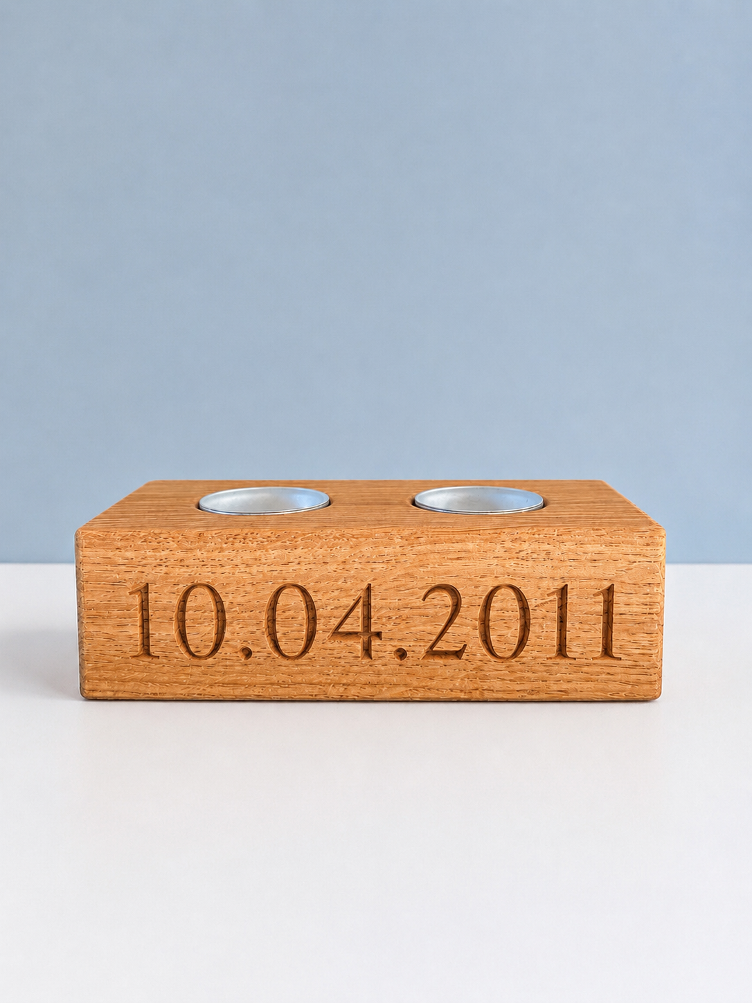 Wooden block with engraved date '10.04.2011' on a white surface with a light blue background