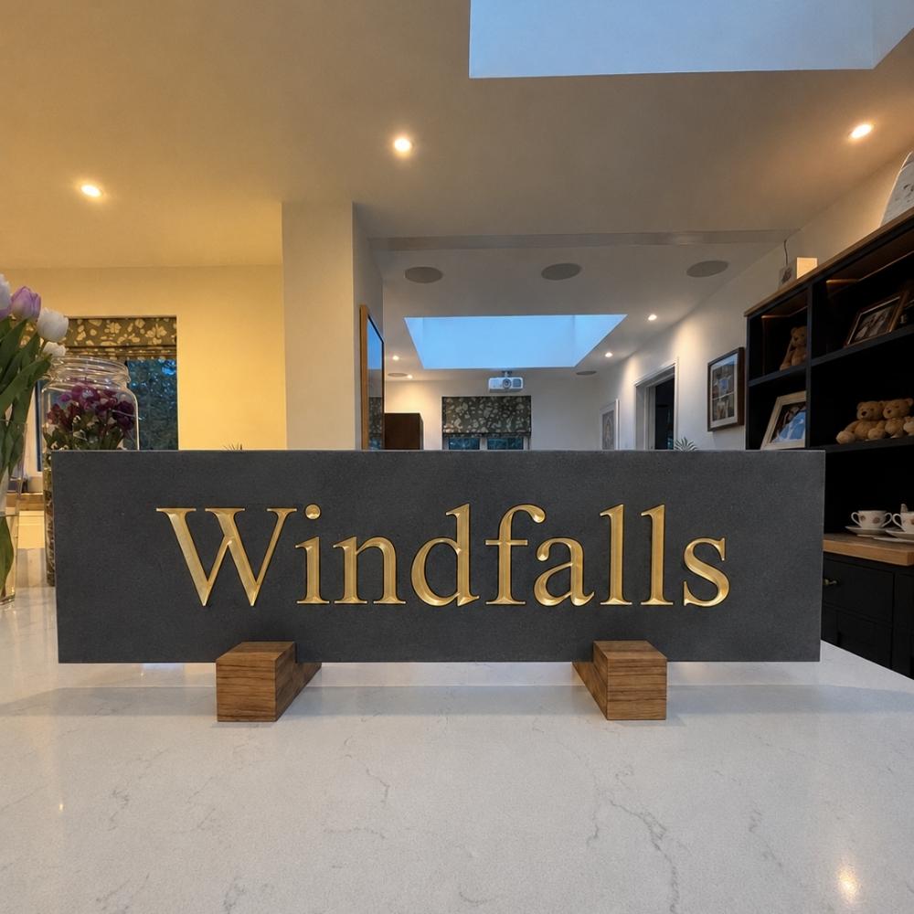 A large slate horizontal sign with the word 'Windfalls' in gold lettering.