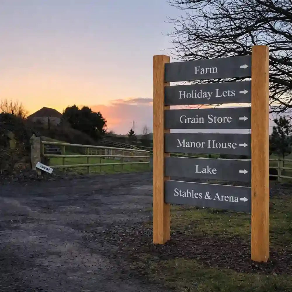 Directional signpost in a rural setting with a sunset sky.