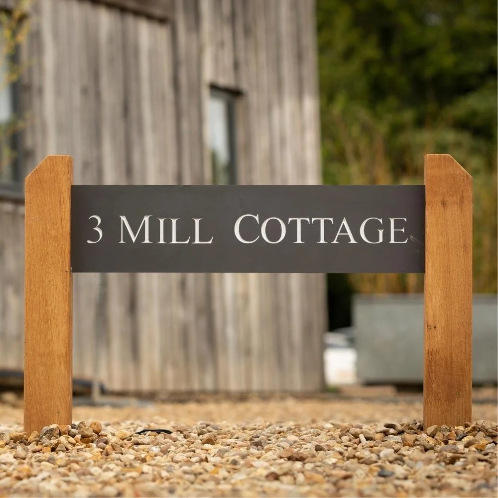 Wooden sign with '3 Mill Cottage' text in front of a wooden building.