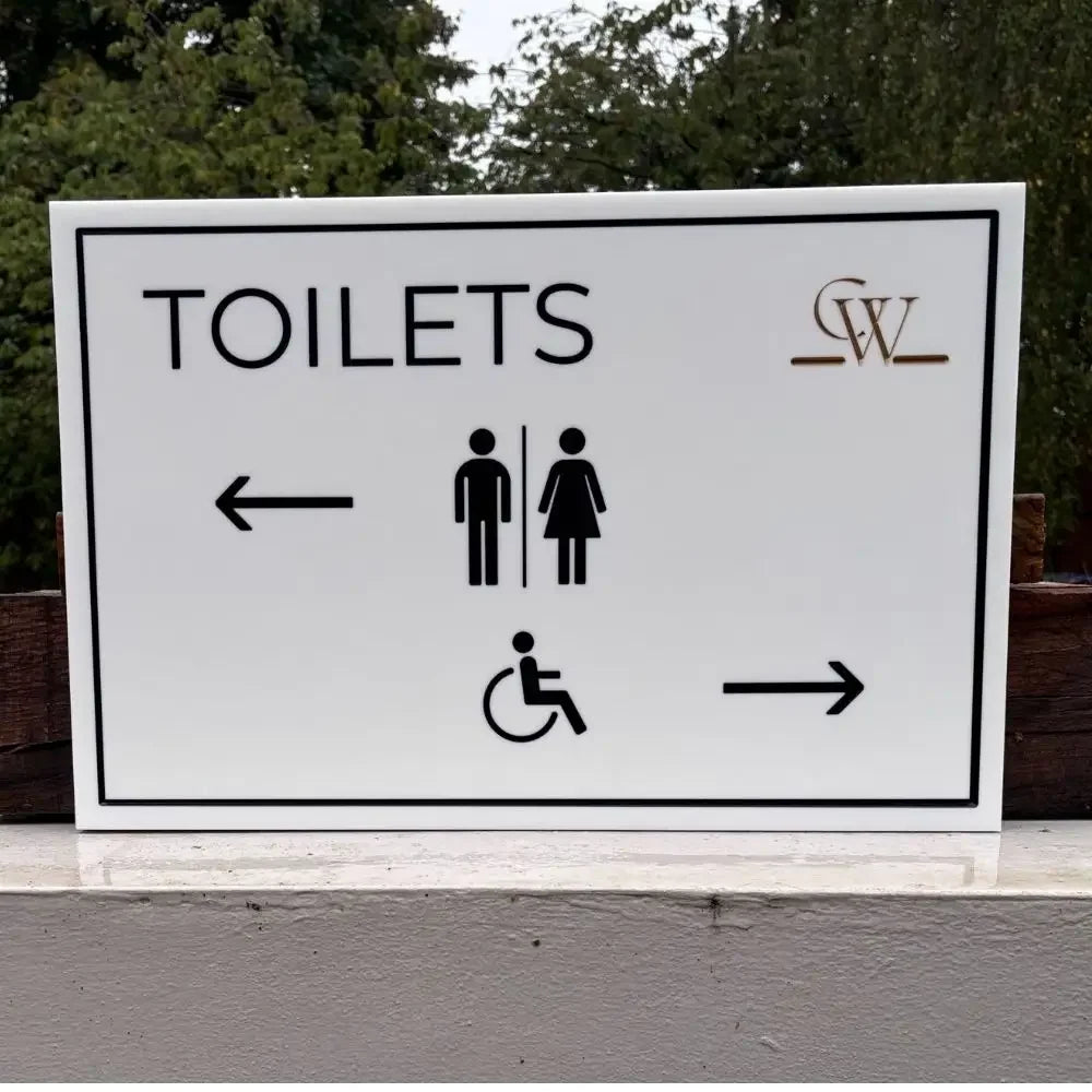 Toilets sign with directional arrows and accessibility icon on a white background