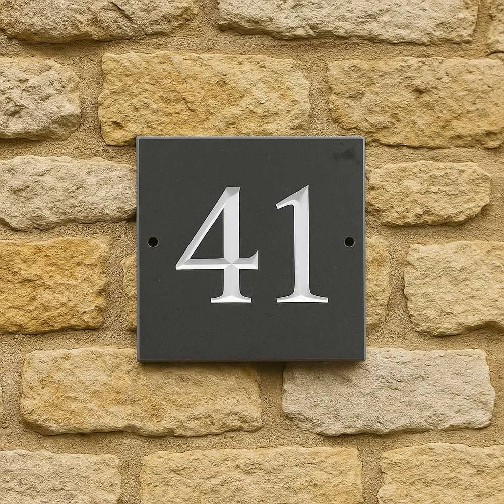 House number '41' on a dark gray square plaque against a stone wall.