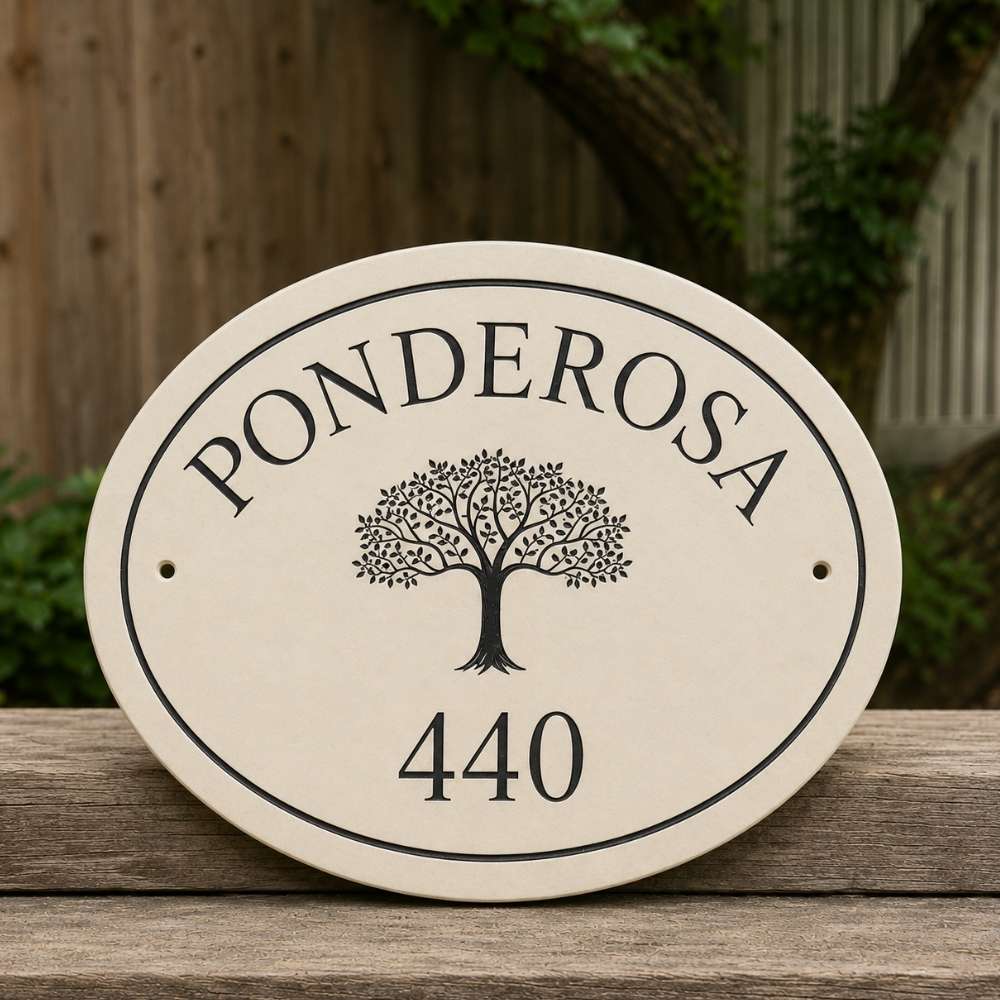 An oval limestone house plaque with a black border, featuring the name 'PONDEROSA' in arched lettering above a stylized tree and the number '440' below, displayed on a wooden surface with a blurred outdoor background.
