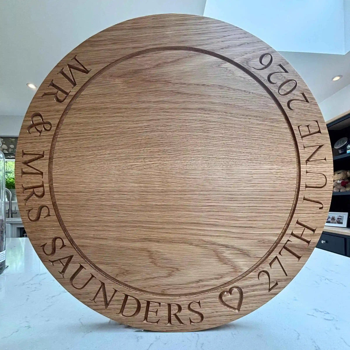 Wooden round cutting board with engraved text on a white surface