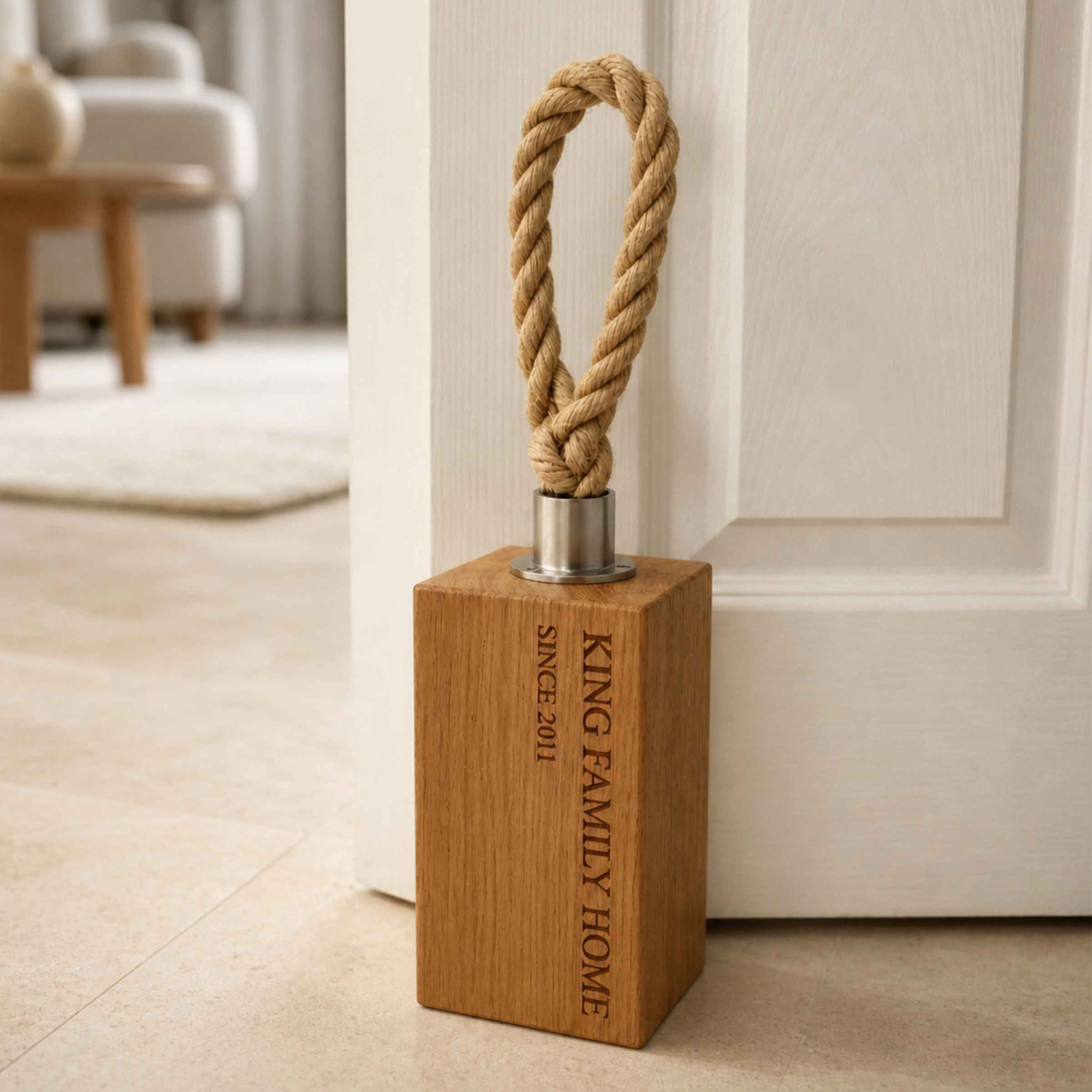 Wooden door stopper with engraved text and rope handle in a home setting