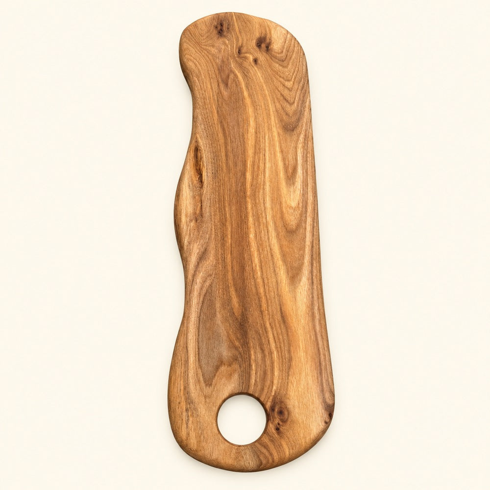 A single wooden serving board or cutting board with a rounded handle shape and a circular hole near the bottom, shown on a plain light background.
