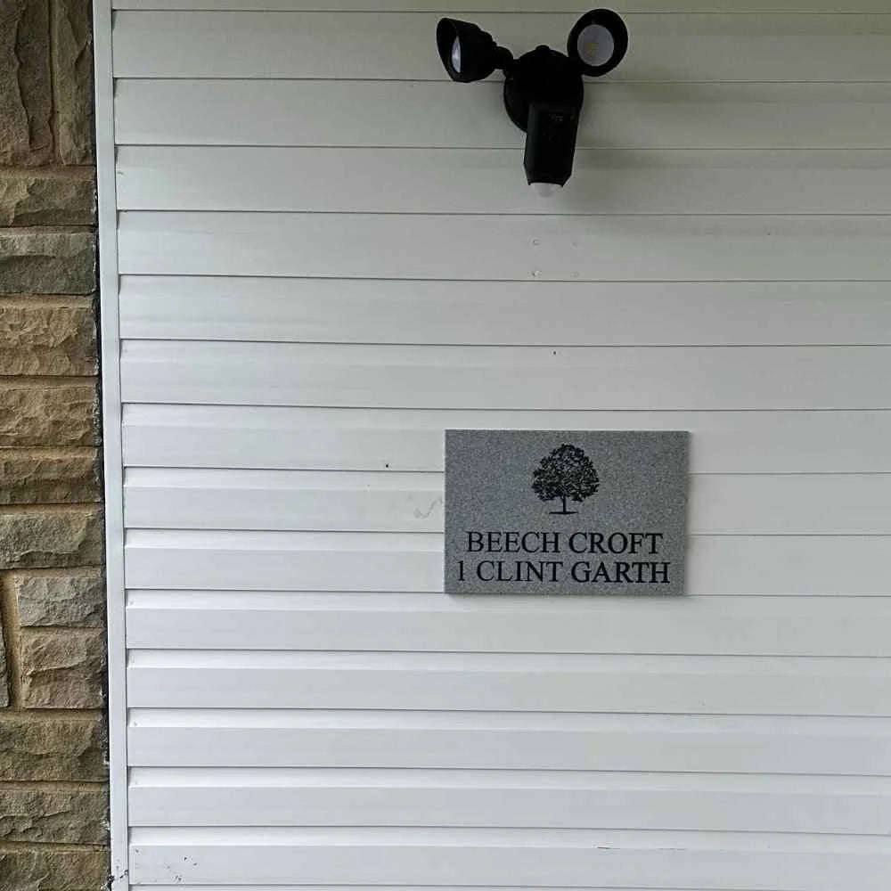 Moose head mounted on a white wall with a house nameplate below it.