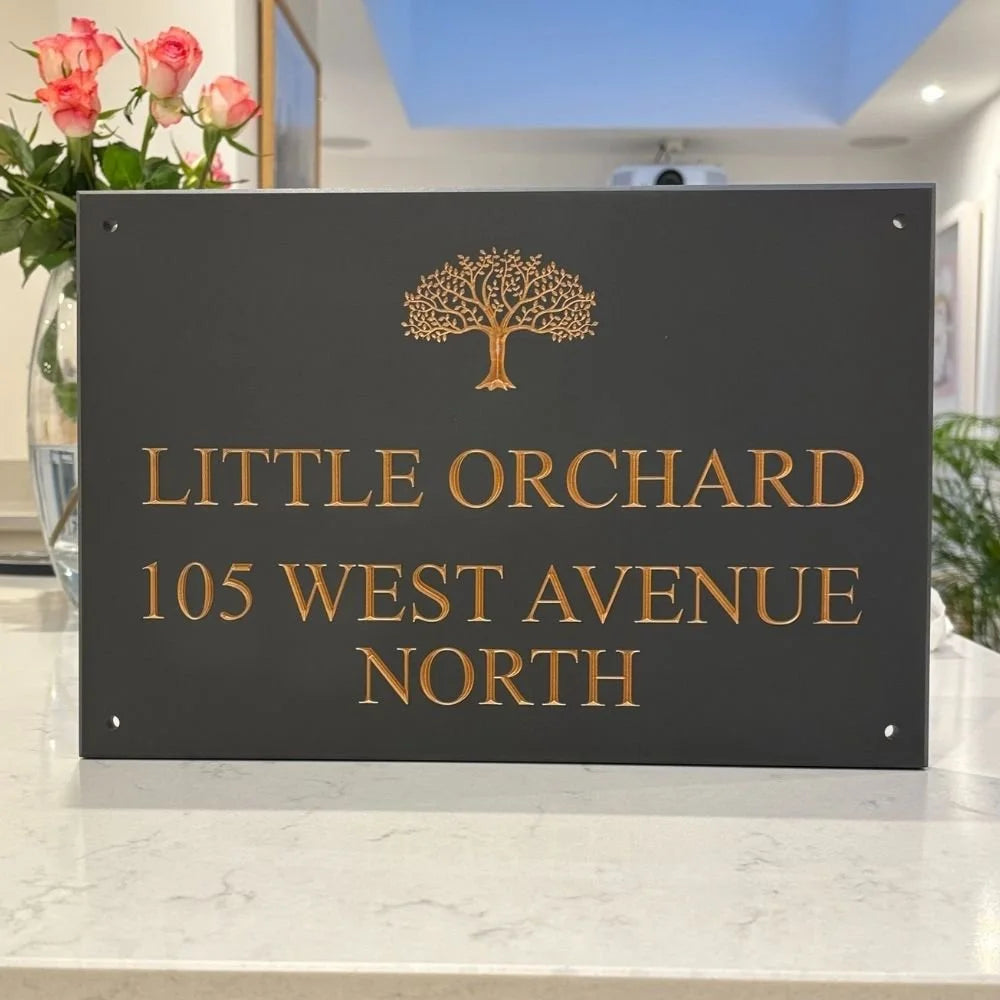 Decorative house sign with 'Little Orchard' and address on a marble surface.
