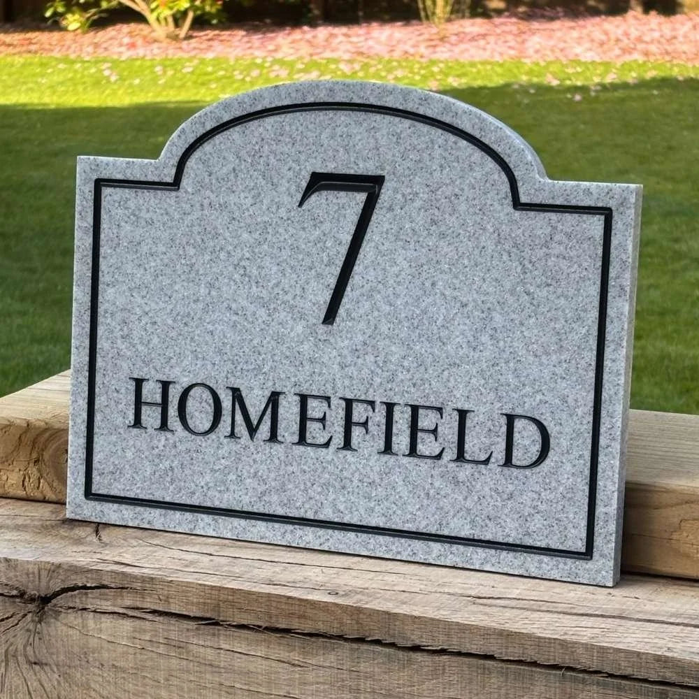 Granite stone house number sign with '7' and 'HOMEFIELD' text on a wooden surface.