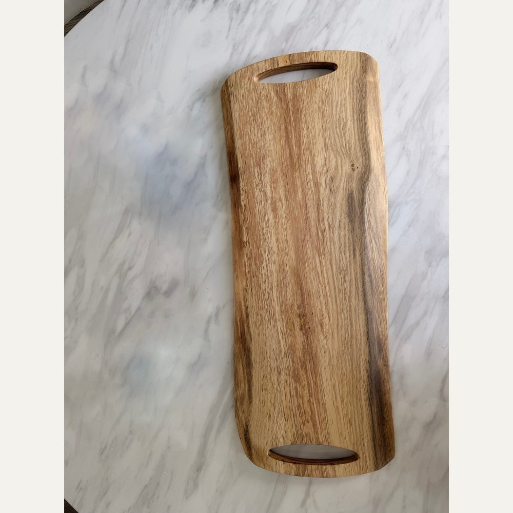 A rectangular wooden serving board with rounded corners and two oval cutouts, one at the top and one at the bottom, shown on a white marble surface.
