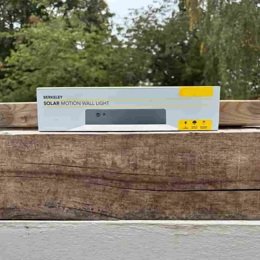 Berkeley solar motion wall light on a wooden surface with trees in the background
