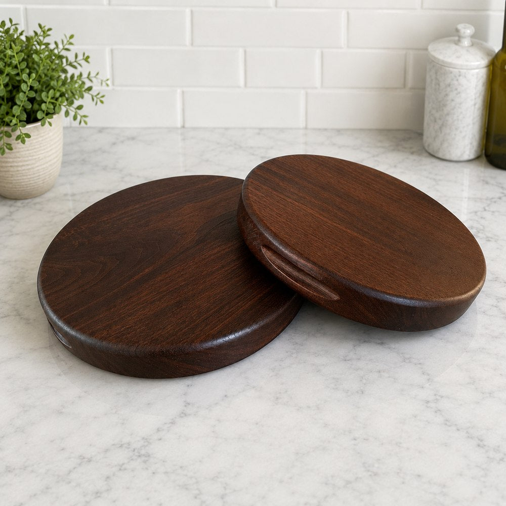 Two round dark wood serving boards with handles, displayed on a white marble countertop with a white subway tile backsplash in the background.